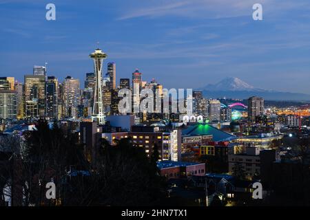 Seattle - 11 febbraio 2022; skyline della città di Seattle con il Monte Rainier mentre le luci si accendono durante una serata invernale Foto Stock