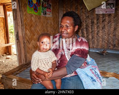 Ostetrica tradizionale con il suo bambino seduto in una capanna di uccelli nella Papua Nuova Guinea rurale Foto Stock