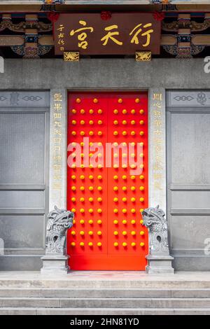 Tradizionale porta rossa del tempio con rivetti gialli o dorati o manopole in linee simmetriche diritte al Tempio Xingtiano di Taipei, Taiwan Foto Stock