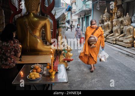 Un monaco buddista thailandese passa statue di Buddha vatious poste all'esterno dello shosp per oggetti buddisti; Bambrung Muang Rd., Bangkok, Thailandia Foto Stock