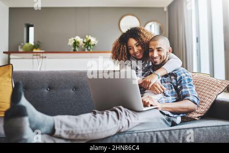 Theres no negando la loro connessione. Scatto di una giovane donna che abbraccia il marito mentre usa un computer portatile sul divano a casa. Foto Stock