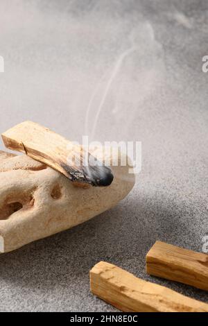 Palo Santo bastone incenso che brucia sulla pietra. Fumo di legno Santo. Pratiche spirituali. Formato verticale. Primo piano. Foto Stock