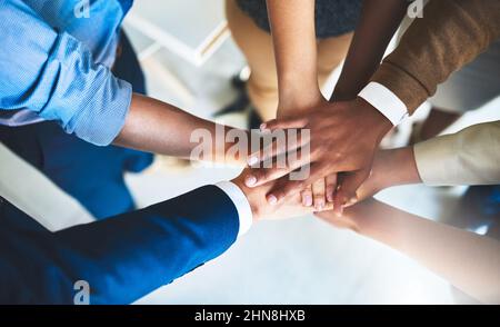 Ci troviamo in una missione comune. Scatto corto di un gruppo di uomini d'affari che si accatastano le mani l'una sull'altra. Foto Stock