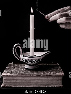 Una mano femminile ha acceso una candela con una corrispondenza che emette fumo dopo che esce Foto Stock