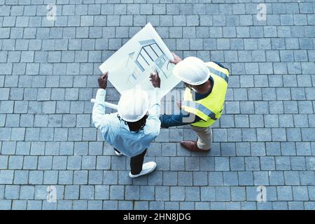 Condividere le sue idee e la sua visione. Scatto ad alta angolazione di due ingegneri che guardano un progetto. Foto Stock