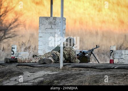 REGIONE DI ZAPORIZHZHIA, UCRAINA - 14 FEBBRAIO 2022 - Un soldato pratica con una mitragliatrice in un campo di tiro al centro di addestramento militare istituito w Foto Stock