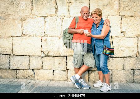 Coppia di anziani felici divertirsi con uno smartphone moderno - concetto di anziani attivi e interazione con le nuove tecnologie - stile di vita di viaggio senza un Foto Stock