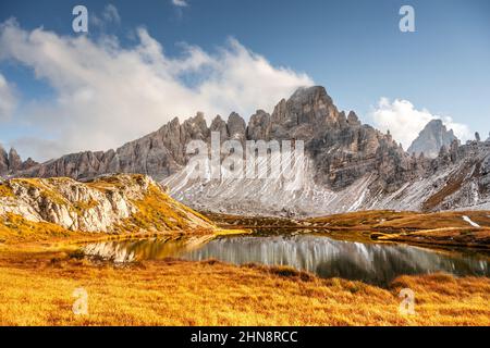 Acque cristalline del lago di Piani nel Parco Nazionale delle tre Cime di Laveredo, Dolomiti, Italia. Paesaggio pittoresco con montagne innevate, erba d'arancio e laghetto in autunno delle Alpi dolomitiche Foto Stock