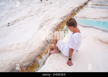 Ritratto emozionale di un giovane seduto di fronte alle piscine in travertino - Castello di cotone nel sud-ovest della Turchia Foto Stock