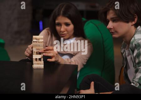 Due amici in cerca di concentrazione, giocando blocchi jenga Foto Stock