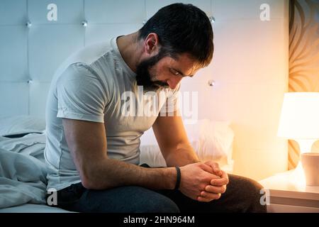 Persona con qualche tipo di problema seduta sul letto e con la testa si inchinò. Foto Stock