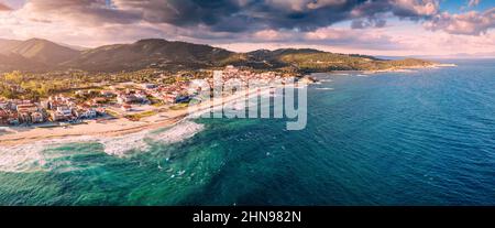 Spettacolare vista aerea panoramica dell'iconica cittadina turistica di Sarti e della famosa spiaggia di sabbia lunga e vuota al tramonto con onde alte. Vacanza su Halkidiki Foto Stock