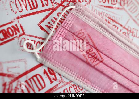 omicron rosso stampigliato su una maschera rosa, primo piano Foto Stock