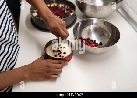 Afro donna che fa formaggio casolare e torta di bacche in cucina a casa Foto Stock
