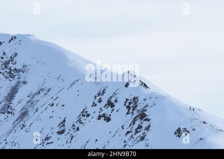 Un gruppo di escursionisti con racchette da neve in viaggio verso una vetta lungo una cresta alpina a Grigioni, in Svizzera. Foto Stock