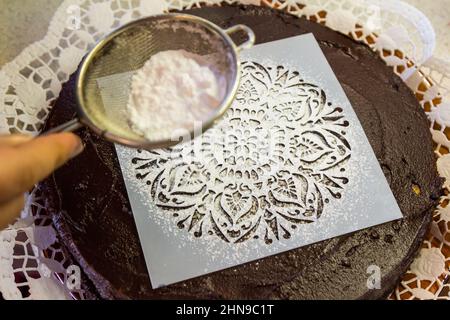 Stencil riutilizzabile per la glassa sulla torta al cioccolato, cosparso di dolcificante sostitutivo dello zucchero Foto Stock