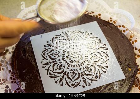 Stencil riutilizzabile per la glassa sulla torta al cioccolato, cosparso di dolcificante sostitutivo dello zucchero Foto Stock