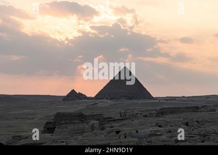 Il complesso archeologico delle grandi piramidi egiziane si trova sull'altopiano di Giza. Luce notturna al tramonto. il sole tramonta dietro la piramide. Foto Stock