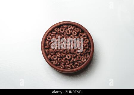 Ciotola in legno con cereali per la colazione rapida al cioccolato su dorso bianco Foto Stock