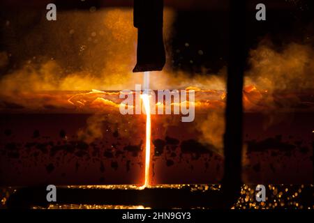 Produzione di barre quadrate in acciaio dolce con colata continua. Barre di taglio con cannello a gas. Fumo e scintille. Foto Stock