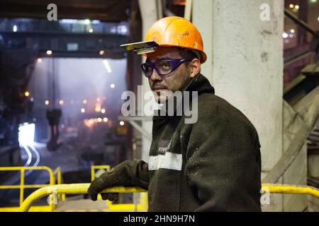 Temirtau, Kazakistan - 08 giugno 2012: Fonderia Arcelor Mittal. Primo piano foto di giovane metallurgista con volto sporco in hardHat arancione e gl protettivo Foto Stock