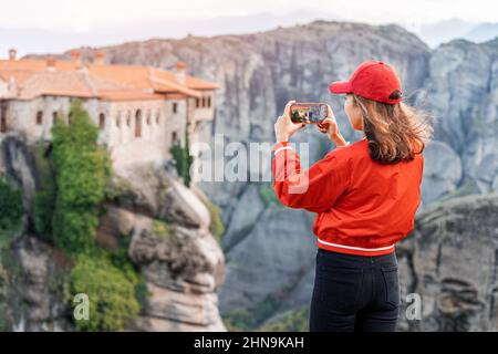 Ragazza turistica che scatta foto sullo smartphone del panoramico Monstery Meteora di Varlaam vicino alla città di Kalabaka. Giro turistico e di viaggio blogger concetto Foto Stock