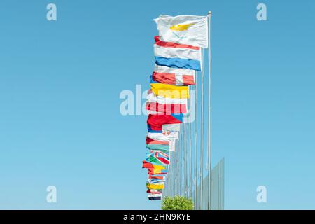 Vista ad angolo basso delle bandiere di vari membri delle Nazioni Unite che sbattono sul vento contro il cielo blu Foto Stock