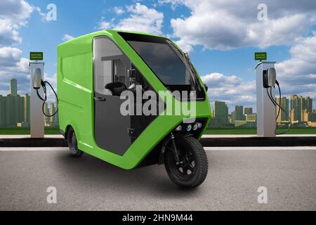 Concetto di scooter triciclo elettrico a consegna verde con stazione di ricarica su sfondo urbano Foto Stock