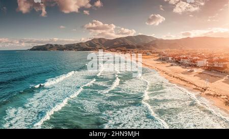 Spettacolare vista aerea panoramica dell'iconica cittadina turistica di Sarti e della famosa spiaggia di sabbia lunga e vuota al tramonto con onde alte. Vacanza su Halkidiki Foto Stock