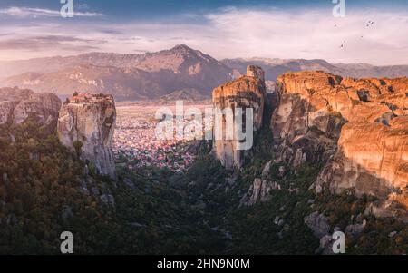 Vista panoramica panoramica sul Monastero della Santissima Trinità a Meteora all'alba e sulla città di Kalambaka in lontananza. Esperienza turistica e di pellegrinaggio Foto Stock