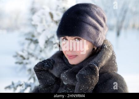 Ritratto di una donna di 40 anni in abiti invernali su sfondo di neve. Foto Stock