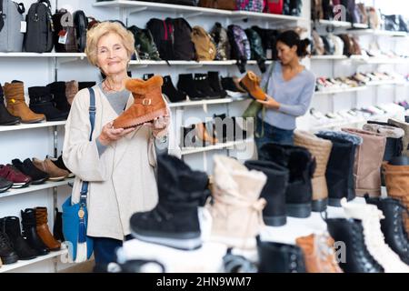 Donna europea matura sceglie stivali invernali Foto Stock