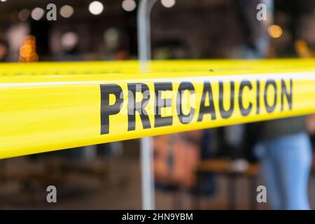 Il testo di avvertenza su un nastro giallo in lingua spagnola all'ingresso di un negozio a Playa del Carmen, Messico. Sfondo sfocato Foto Stock