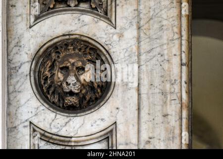 Primo piano di una porta con un bassorilievo in marmo raffigurante la testa di un leone, Torino, Piemonte, Italia Foto Stock