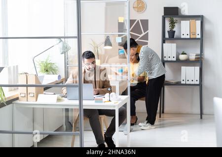 Giovani uomini d'affari che cooperano in uffici moderni, lavorano con documenti e usano computer Foto Stock