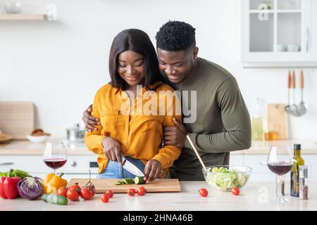 Romantico giovane coppia Nero pranzo di cottura in cucina e bere vino rosso Foto Stock