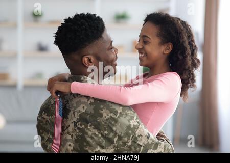 Ragazza allegra con bandiera degli Stati Uniti abbracciando suo padre Foto Stock