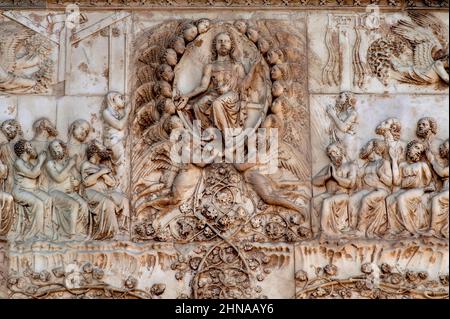 Gesù Cristo mostra le ferite della sua Crocifissione mentre siede nel giudizio, circondato da angeli di sostegno, nel bassorilievo in marmo del giudizio universale del 1300 sul fronte occidentale del Duomo di Orvieto, Umbria, Italia. Questa scena scolpita è attribuita a Lorenzo Maitani (c. 1275 - 1330), che progettò la facciata tardo gotica della cattedrale. Si ritiene che Maitani abbia avuto un contributo diretto come scultore su due pannelli che coprono due dei quattro pilastri inferiori della facciata: Un pannello Maitani raffigura scene del giudizio universale, compresa la scena in questa immagine. Foto Stock