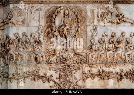 Gesù Cristo siede nel giudizio, mostrando le sue ferite da crocifissione e circondato da angeli di sostegno, nel bassorilievo in marmo del giudizio universale del 1300 sul fronte occidentale del Duomo di Orvieto, Umbria, Italia. Questa scena scolpita è attribuita a Lorenzo Maitani (c. 1275 - 1330), che progettò la facciata tardo gotica della cattedrale. Si ritiene che Maitani abbia avuto un contributo diretto come scultore su due pannelli che coprono due dei quattro pilastri inferiori della facciata: Un pannello Maitani raffigura scene del giudizio universale, compresa la scena in questa immagine. Foto Stock