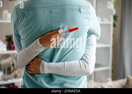 Donna che sorprende suo marito con test di gravidanza positivo, Foto Stock