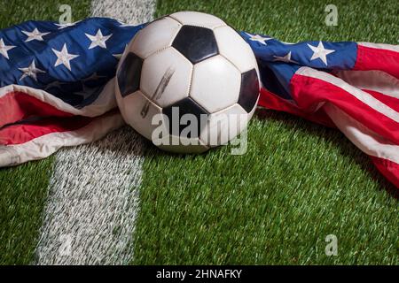 Pallone da calcio e bandiera americana sul campo d'erba con striscia bianca Foto Stock