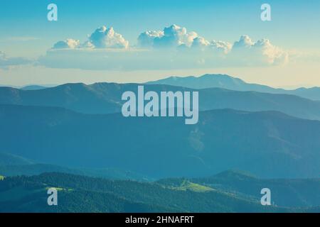 Vista sulle catene blu di montagne sotto il bel cielo nuvoloso prima del tramonto Foto Stock