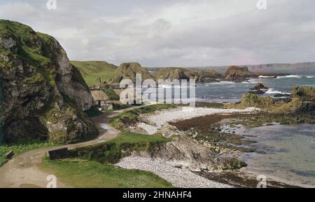 1960s, vista storica da questa epoca di attraverso la pittoresca baia a Ballintoy, Co Antrim, Irlanda del Nord, Regno Unito, che mostra piccole spiagge di ghiaia e costa frastagliata. Più recentemente è stata la location per la serie TV Game of Thrones. Foto Stock