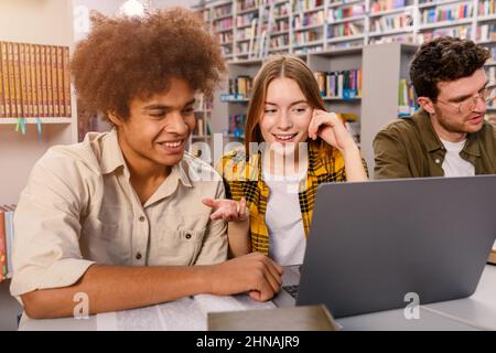 Gli studenti universitari studiano insieme in una biblioteca come lavoro di squadra per la preparazione Foto Stock