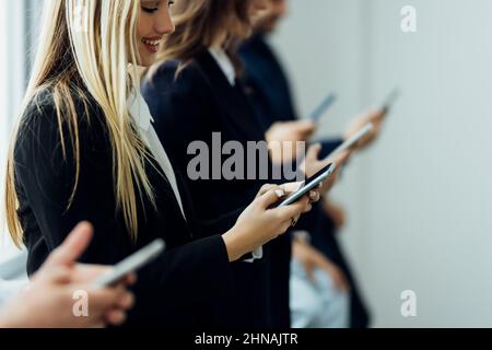 Diverse in bianco e nero delle persone sedute in fila gli smartphone utilizzando compresse, multirazziale gli uomini e le donne in attesa di colloquio di lavoro risorse umane, employm Foto Stock