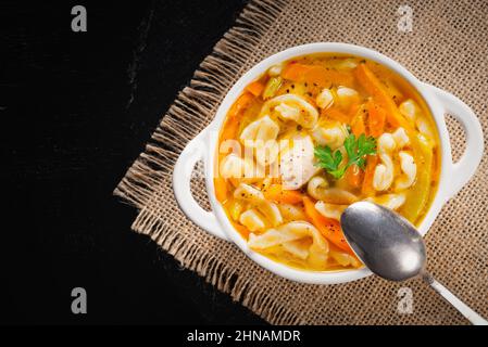 Zuppa di spaghetti di pollo con prezzemolo e verdure in un piatto bianco Foto Stock