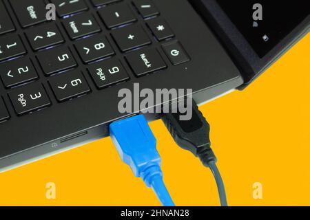 Collegamento di computer e computer portatili a Internet tramite cavi USB. Sfondo giallo con posizione per il testo. Il computer portatile collega l'adattatore del cavo USB-C. Foto Stock