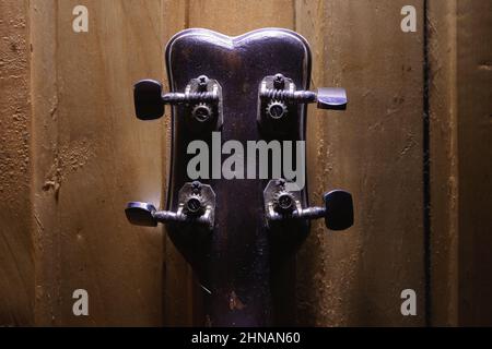 Dettagli di una piccola chitarra con quattro corde, parte posteriore di una testa e piedini. Foto Stock