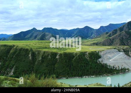 Il fiume Katun ad Altai con una riva molto alta, prato e creste dietro, estate, giorno limpido Foto Stock