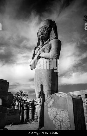 Colossale statua del re Ramesses II con sua figlia Bent'anta, al tempio di Karnak. Realizzato in granito rosso prima della seconda torre nella Corte Grande Foto Stock